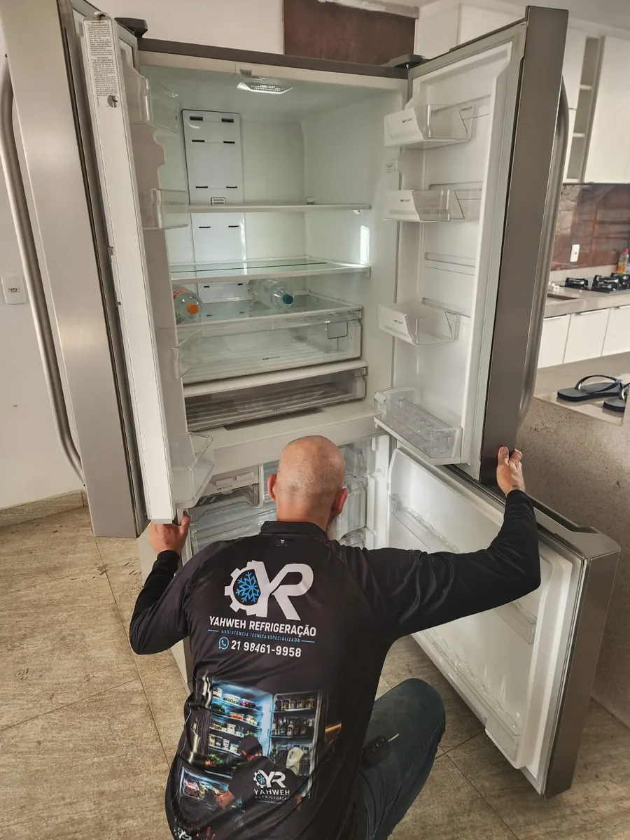 Técnico da Yahweh Refrigeração verificando geladeira inox de duas portas na casa do cliente