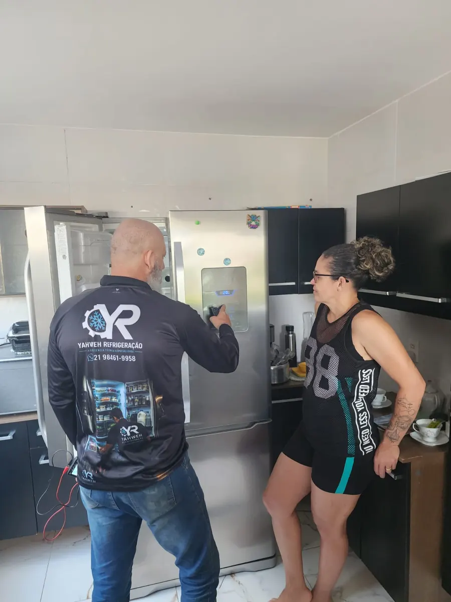 Técnico da Yahweh Refrigeração atendendo cliente e testando o painel da geladeira