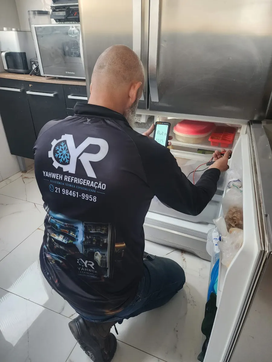Técnico da Yahweh Refrigeração medindo com multímetro o freezer de uma geladeira