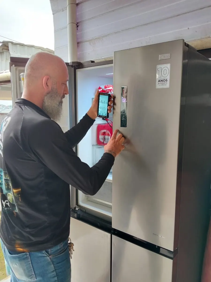 Técnico da Yahweh Refrigeração medindo com multímetro geladeira inverse Midea