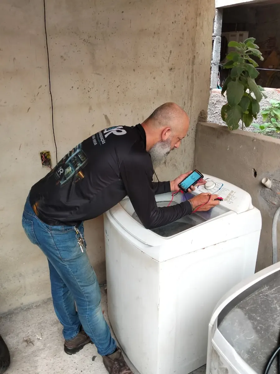 Técnico da Yahweh Refrigeração medindo com multímetro o painel de uma máquina de lavar
